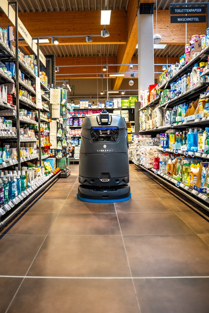 LionsBot R5 wet-cleaning a shelf aisle – full-range supermarket, 900 m²